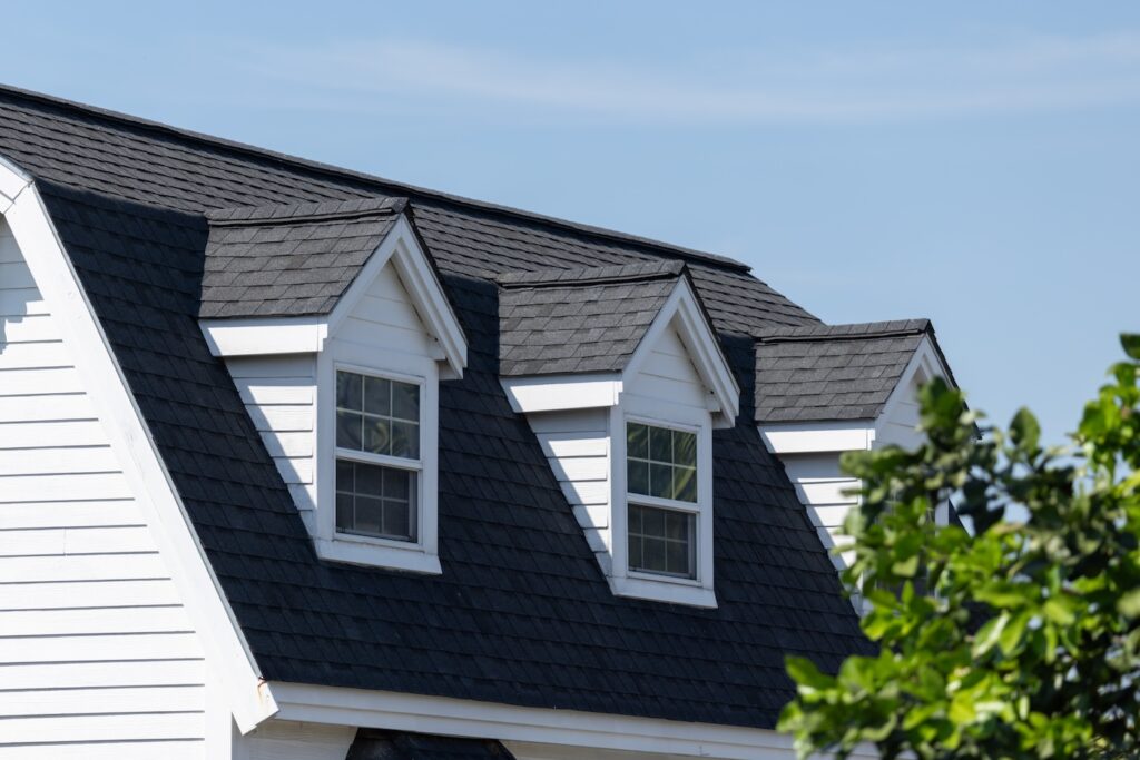 A house with a black roof and white trim. The roof has three windows and a skylight