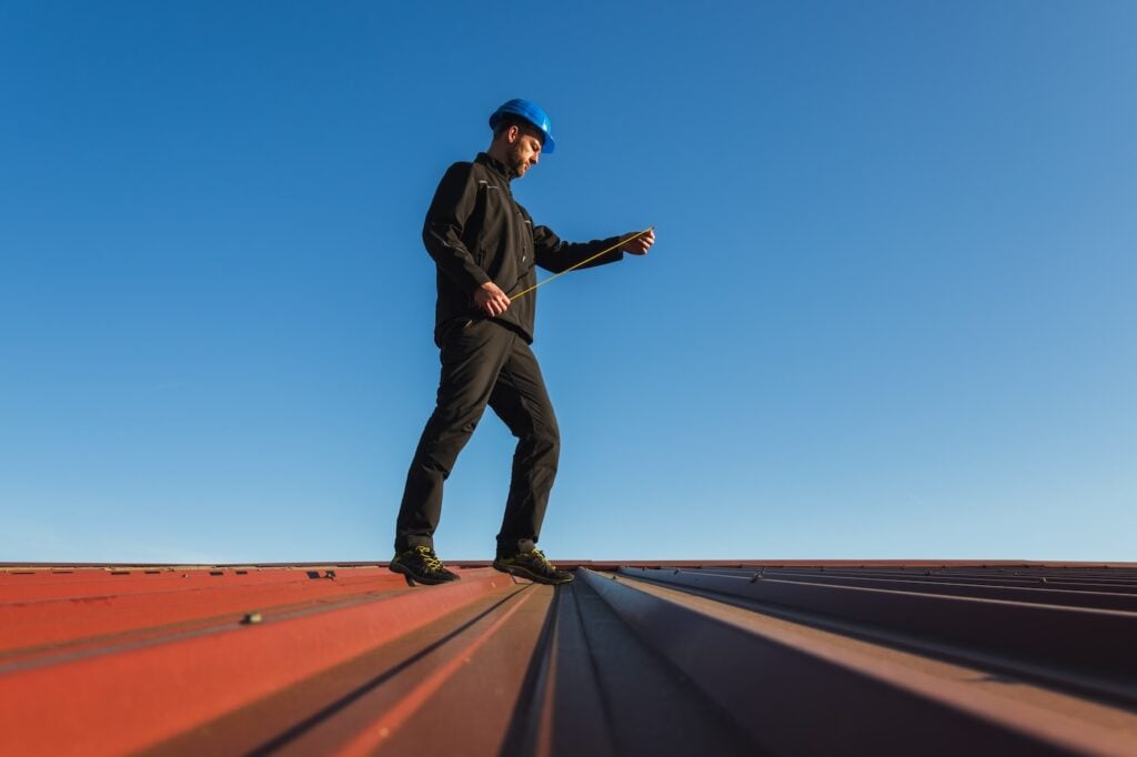 roofer measuring metal roof for installation