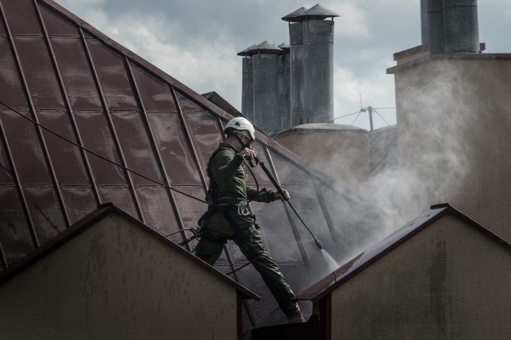 a man washing a roof with pressurized water