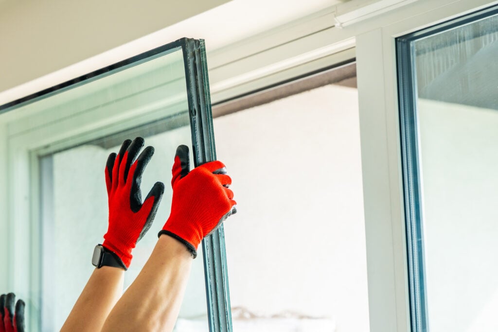 Removed triple glazed window glass unit leaning near frame after replacement in apartment. Broken insulated glass panel removal and window repair process concept