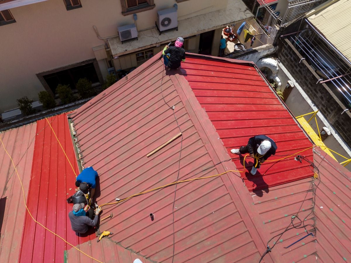 workers repairing red metallic roof